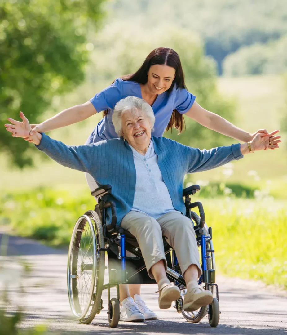 Rollstuhlfahrerin mit Pflegerin Rollstuhlfahrerin mit Pflegerin im Park unterwegs bei Sonnenschein