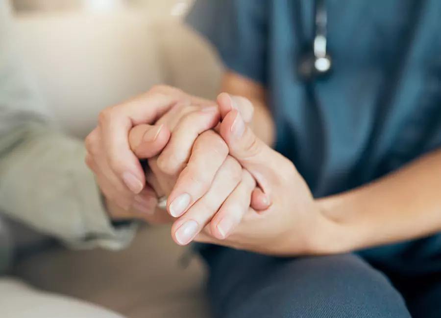 Eine Pflegerin hält die Hand einer Seniorin.