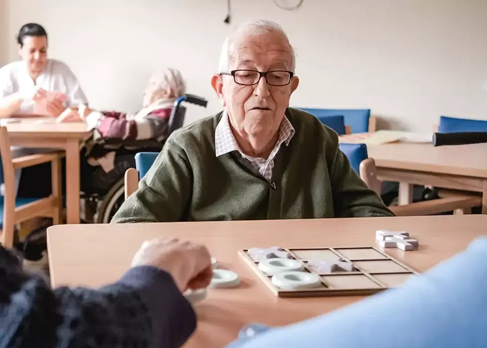 shutterstock-2470591841-6710b5c7474f5 Senior spielt im Aufenthaltsraum ein einfaches Brettspiel mit seinem Pfleger